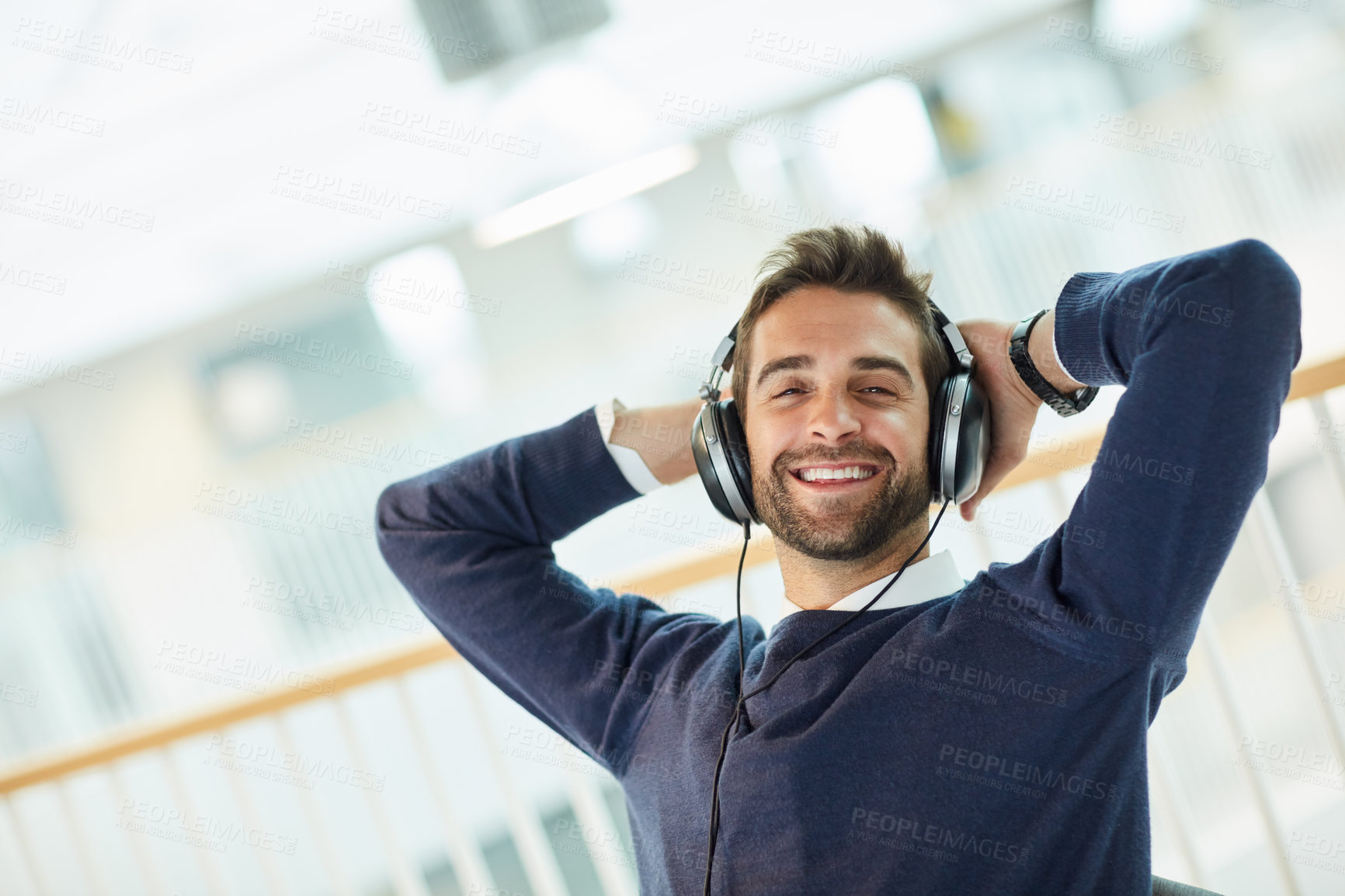 Buy stock photo Portrait of a young businessman listening to music in an office