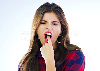 Buy stock photo Studio shot of a young woman sticking her finger down her throat