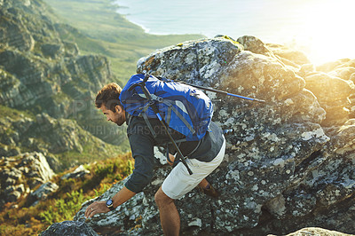 Buy stock photo Shot of a young man hiking up a mountain