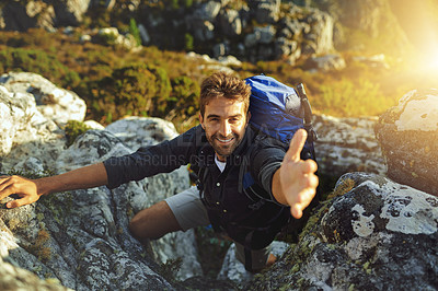 Buy stock photo Shot of a young man extending his hand to help while hiking up a mountain