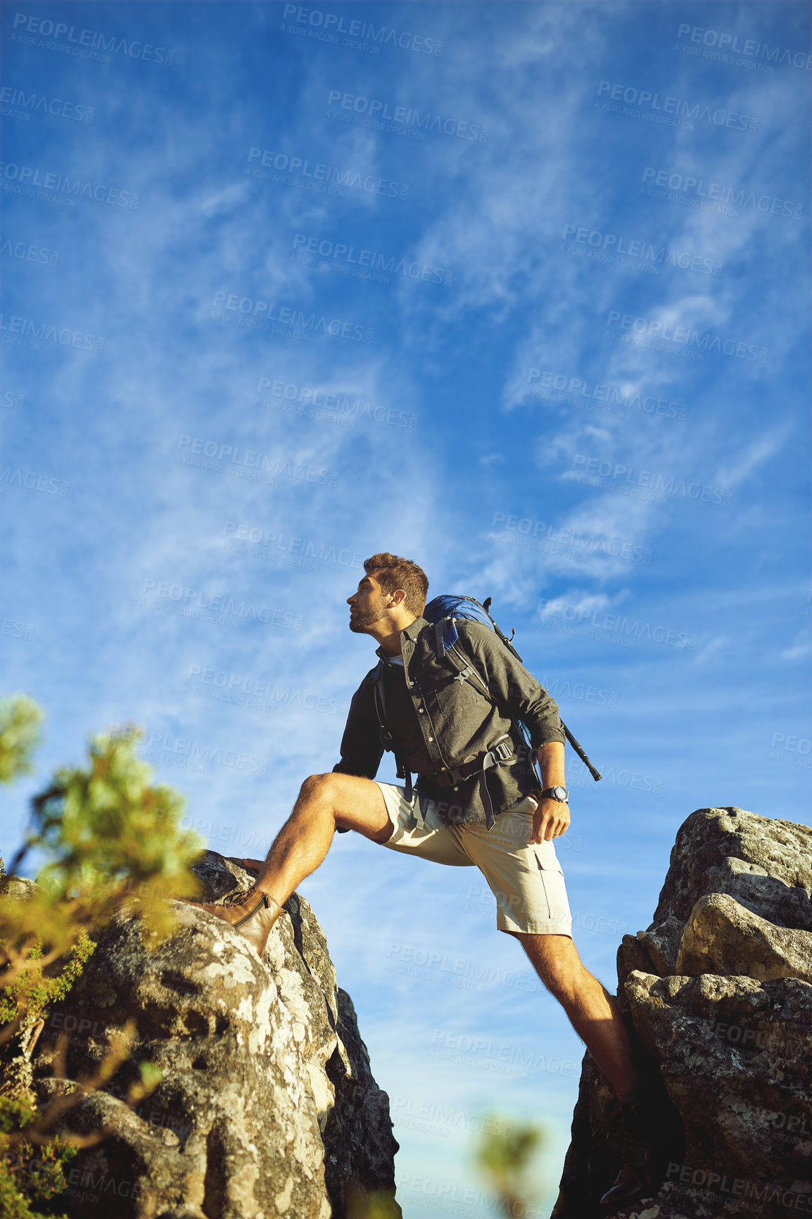 Buy stock photo Shot of a young man hiking up a mountain