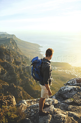 Buy stock photo Shot of a young man hiking up a mountain
