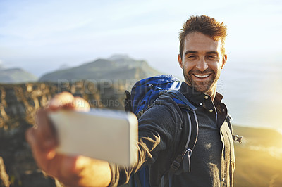 Buy stock photo Shot of a young man taking selfies while hiking up a mountain