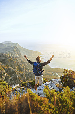 Buy stock photo Shot of a young man cheering while hiking up a mountain
