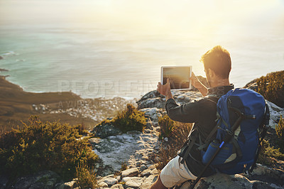 Buy stock photo Shot of a young man taking photographs of the view while hiking up a mountain