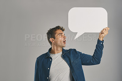 Buy stock photo Studio shot of a young man holding a speech bubble against a grey background