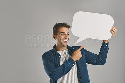 Buy stock photo Studio portrait of a young man pointing to a speech bubble against a grey background