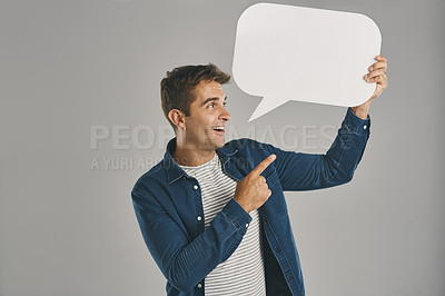 Buy stock photo Studio shot of a young man pointing to a speech bubble against a grey background