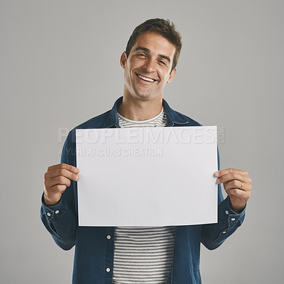 Buy stock photo Studio portrait of a young man holding a blank placard against a grey background