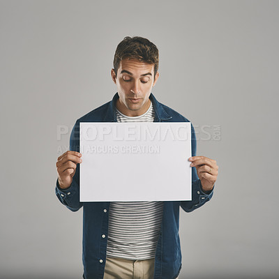 Buy stock photo Studio shot of a young man holding a blank placard against a grey background