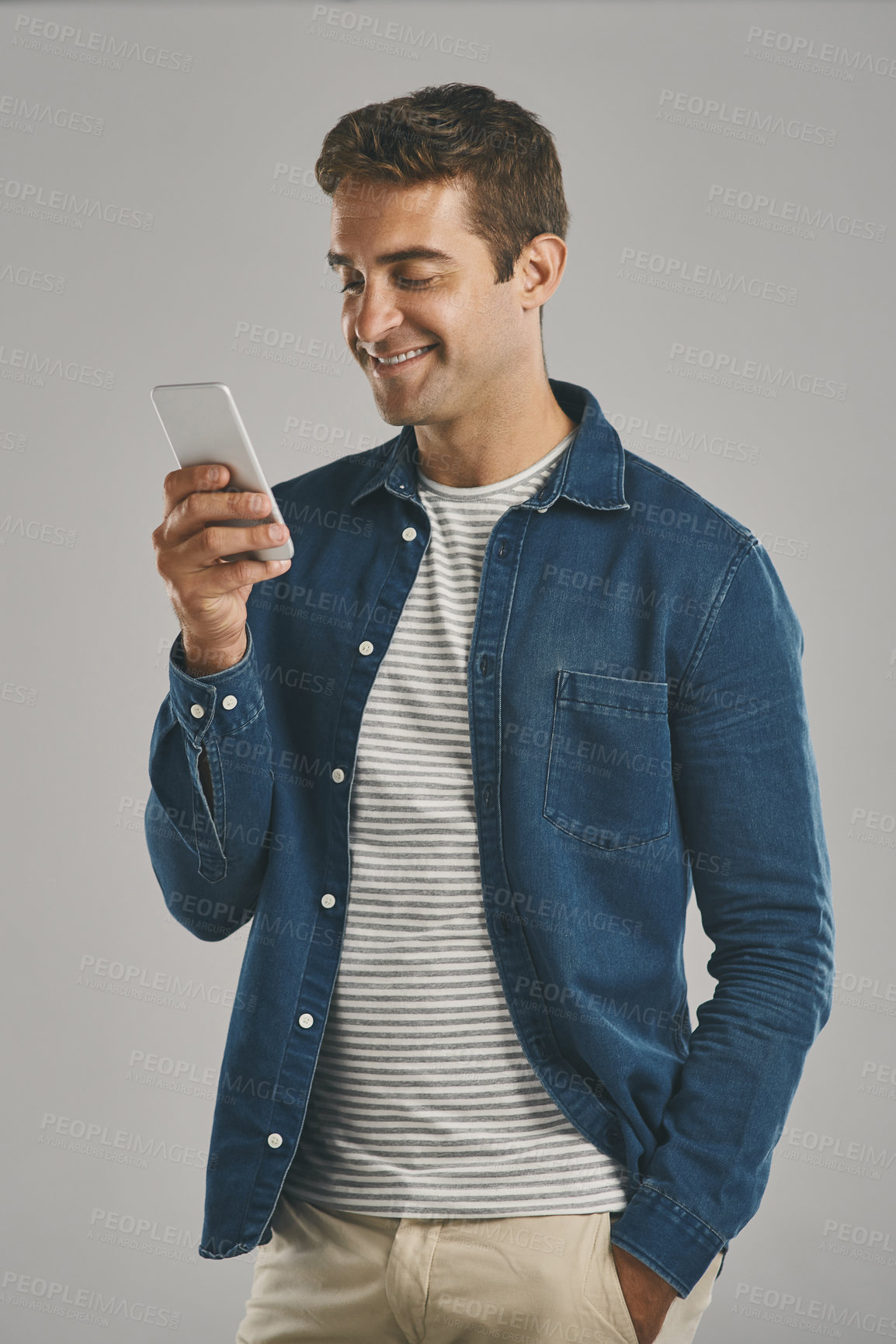 Buy stock photo Studio, man and smartphone for chatting, networking and funny news with contact on social media. Creative worker, scroll and browse on dating app with humor, text and connection by gray background