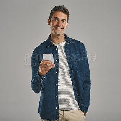 Buy stock photo Studio portrait of a young man using a cellphone against a grey background