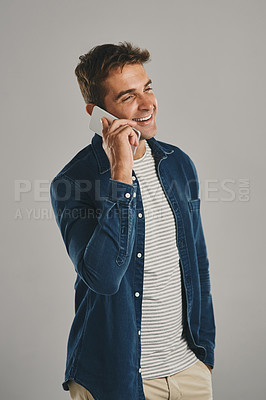 Buy stock photo Studio shot of a young man talking on a cellphone against a grey background