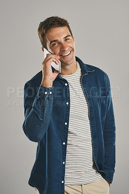 Buy stock photo Studio portrait of a young man talking on a cellphone against a grey background