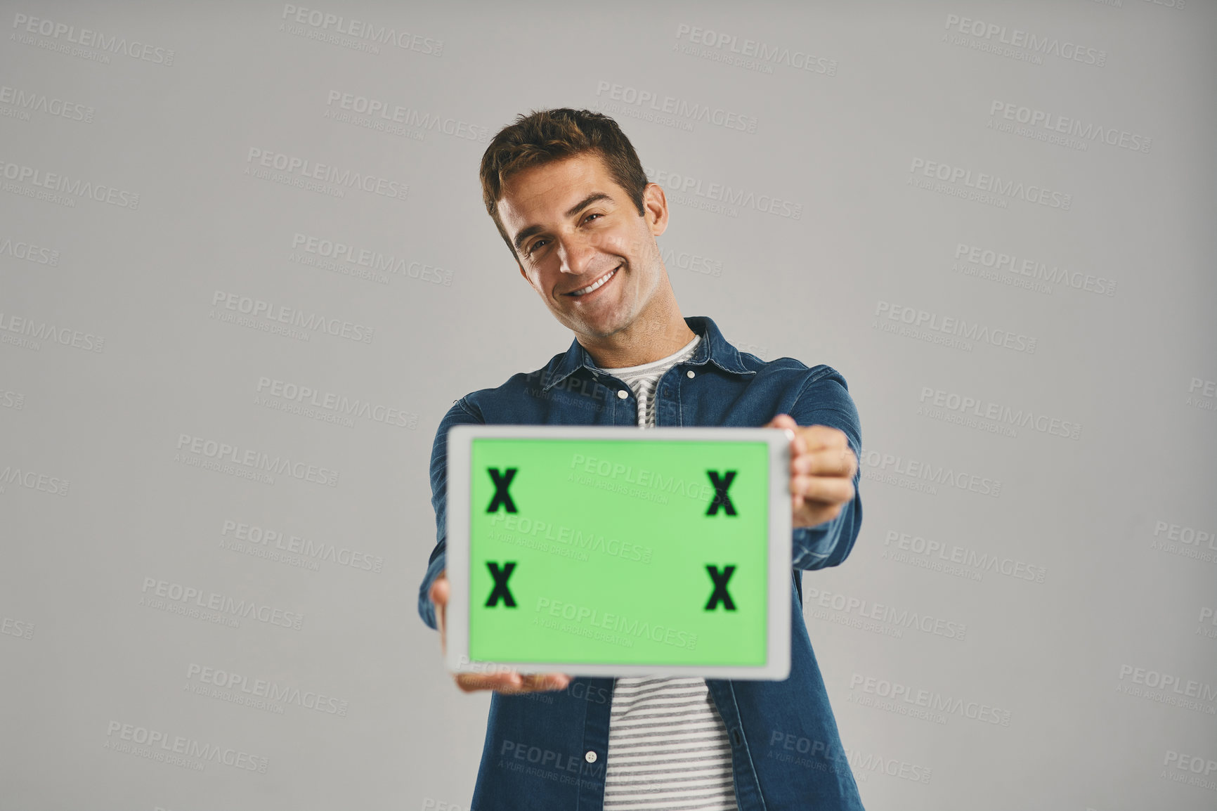 Buy stock photo Studio portrait of a young man holding a digital tablet with a green screen against a grey background