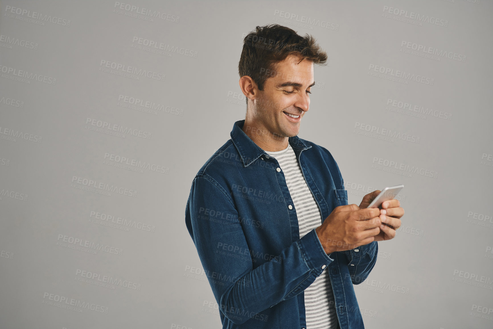 Buy stock photo Texting, man and smile with smartphone in studio for social media, post or mobile app on white background. Male person, happy and mockup space with internet or online for communication and networking