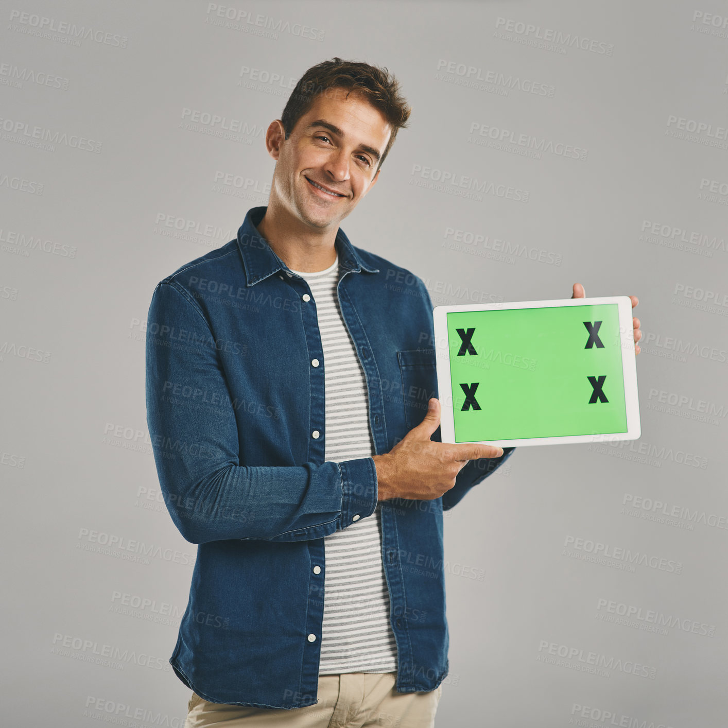 Buy stock photo Studio portrait of a young man holding a digital tablet with a green screen against a grey background