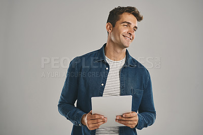 Buy stock photo Studio shot of a young man using a digital tablet against a grey background