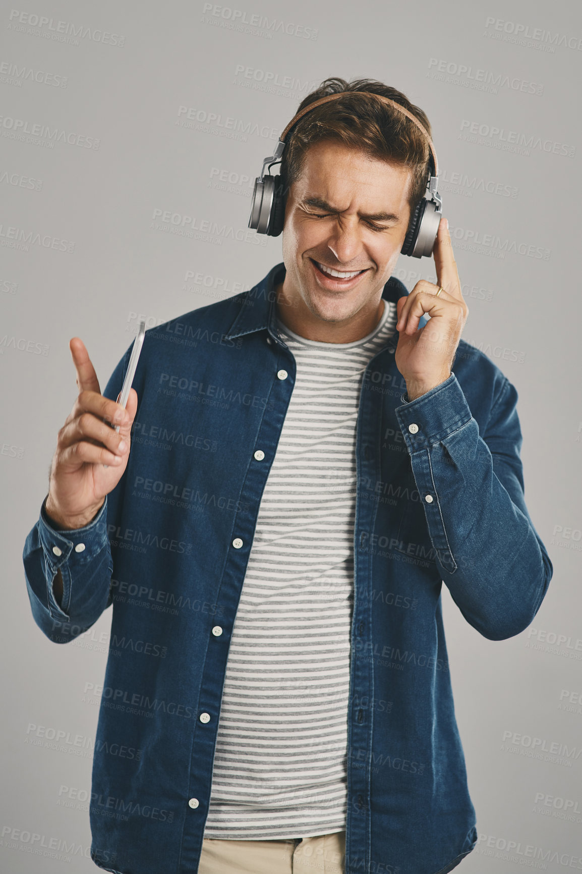 Buy stock photo Man, studio and smartphone on headphones with eyes closed for streaming music, album and playlist on gray background. Male person, mockup space and happy or smile on website, online and subscription