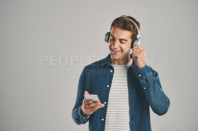 Buy stock photo Man, studio and smartphone on headphones with happiness  for streaming music, album or playlist on gray background. Male person, mockup space and smile or satisfied on website, online or subscription