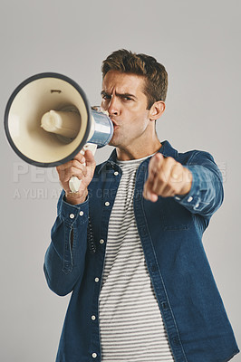 Buy stock photo Studio portrait of a young man talking into a megaphone against a grey background