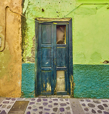 Buy stock photo Old abandoned house or home with a weathered green wall and blue wooden door. Vintage and aged residential building built in a traditional architectural style or design with a cobble stone road