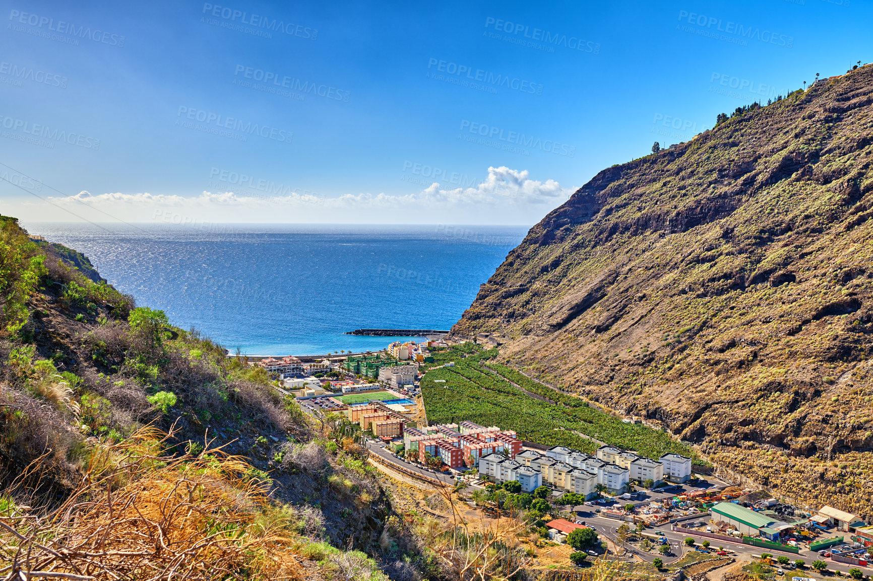Buy stock photo Mountain, ocean and valley with view of village outdoor in natural environment for ecology. Blue sky, horizon and sea with rocky terrain in scenic nature of Spain for landscape or plantation