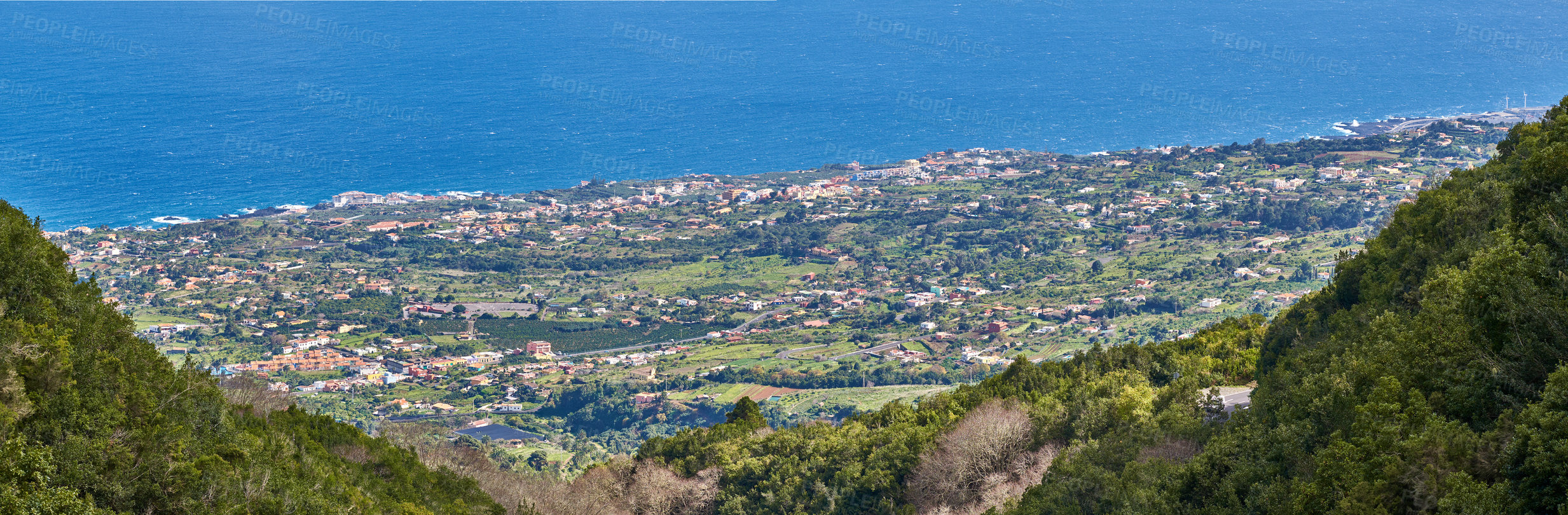 Buy stock photo View of the coastal city, Puerto de Tazacorte, from the mountain with the sea in the background from above. Houses or holiday accommodation by the ocean in the tourist destination of La Palma, Spain