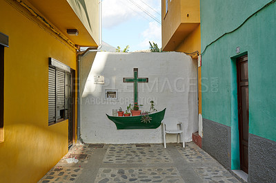 Buy stock photo Historic colorful buildings with a white wall with a crucifix on it in the city of Santa Cruz de La Palma. Antique homes or houses built by vintage architecture in small town or village on sunny day