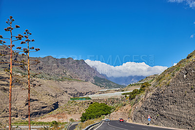 Buy stock photo Beautiful landscape of a countryside tar road with a cloudy blue sky and copy space. Roadway with cars driving to holiday destination through the mountains in Spain on a summer afternoon or day