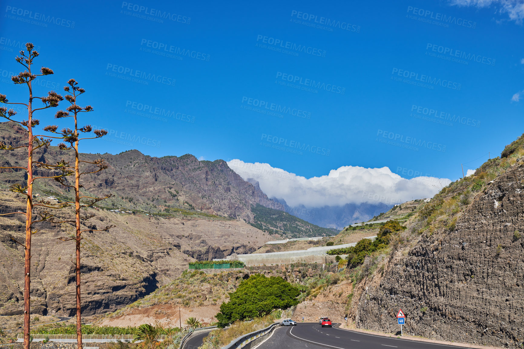 Buy stock photo Beautiful landscape of a countryside tar road with a cloudy blue sky and copy space. Roadway with cars driving to holiday destination through the mountains in Spain on a summer afternoon or day