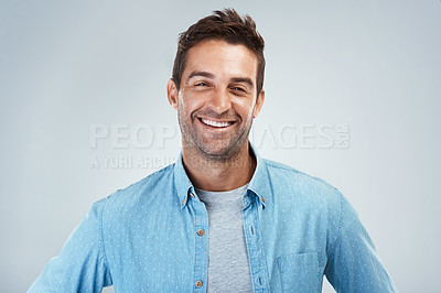 Buy stock photo Portrait of a cheerful young man smiling brightly while standing against a grey background