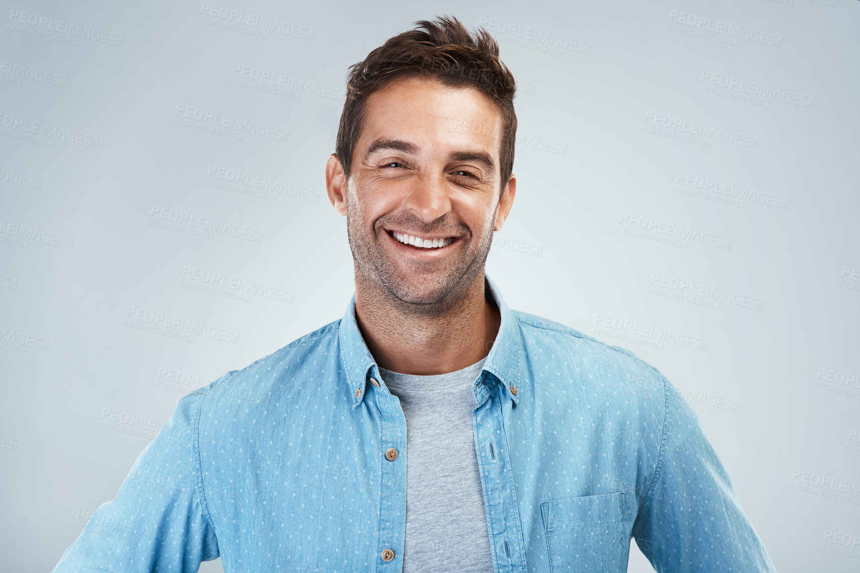 Buy stock photo Portrait of a cheerful young man smiling brightly while standing against a grey background