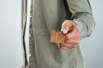 Buy stock photo Cropped shot of an unrecognizable man holding out his credit card while standing against a grey background