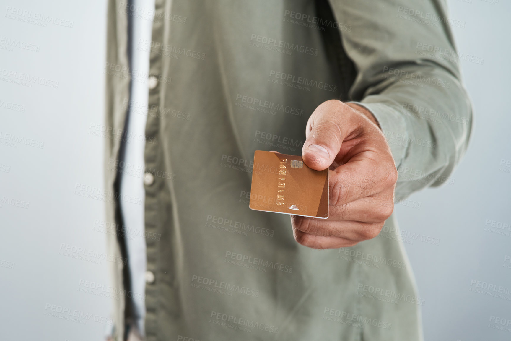 Buy stock photo Cropped shot of an unrecognizable man holding out his credit card while standing against a grey background