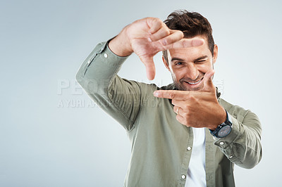 Buy stock photo Portrait of a cheerful young man making frames with his hands to simulate the angle of a camera while standing against a grey background