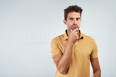 Buy stock photo Portrait of a carefree young man with a confused facial expression on his face while standing against a grey background