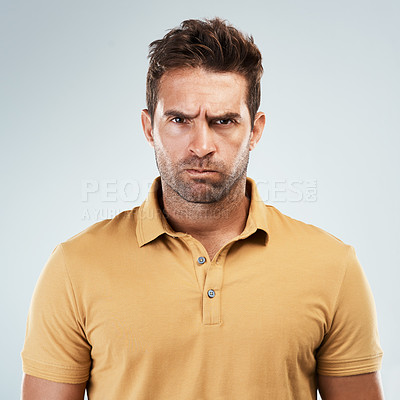 Buy stock photo Portrait of a young man with an angry expression on his face while standing against a grey background