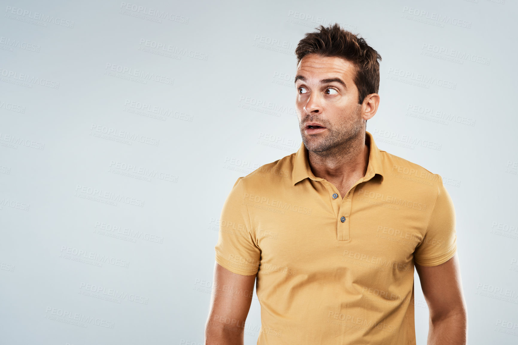 Buy stock photo Studio shot of a young man with a scared facial expression while standing against a grey background