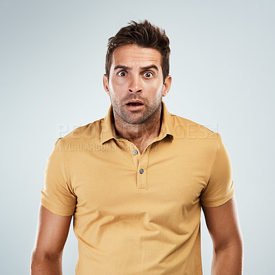 Buy stock photo Portrait of a young man with a scared facial expression while standing against a grey background