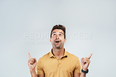 Buy stock photo Man, pointing and excited on studio mockup for deal, promotion and coming soon. Male promoter, wow and up hand gesture on gray background space for announcement, information and happy for opportunity