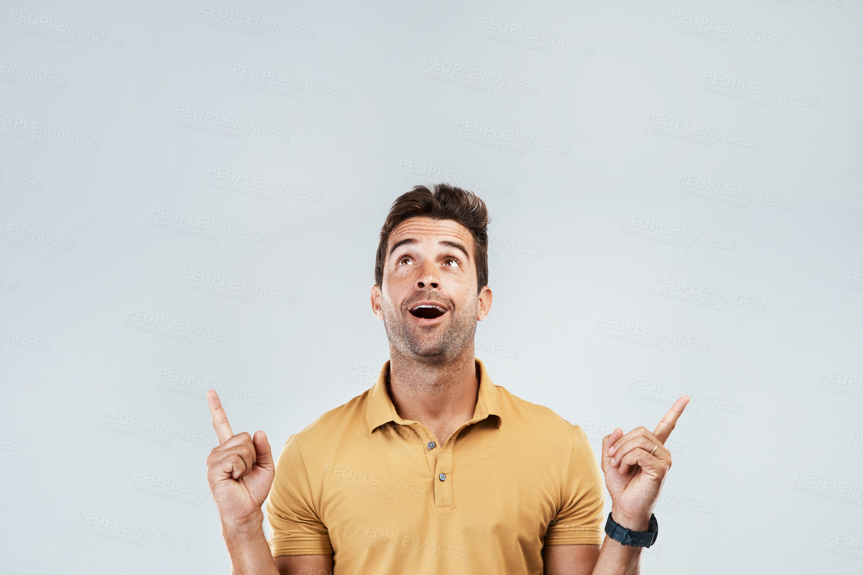 Buy stock photo Man, pointing and excited on studio mockup for deal, promotion and coming soon. Male promoter, wow and up hand gesture on gray background space for announcement, information and happy for opportunity