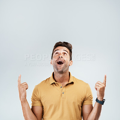 Buy stock photo Man, pointing and happy on studio mockup for deal, promotion and coming soon. Male promoter, wow and up hand gesture on gray background space for announcement, information and excited for opportunity