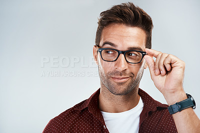 Buy stock photo Studio shot of a cheerful young man wearing glasses and smiling brightly while standing against a grey background