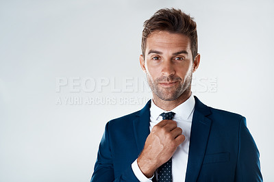 Buy stock photo Portrait of a confident young businessman wearing a suit while standing against a grey background