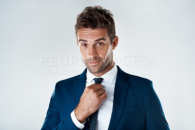 Buy stock photo Portrait of a confident young businessman wearing a suit while standing against a grey background