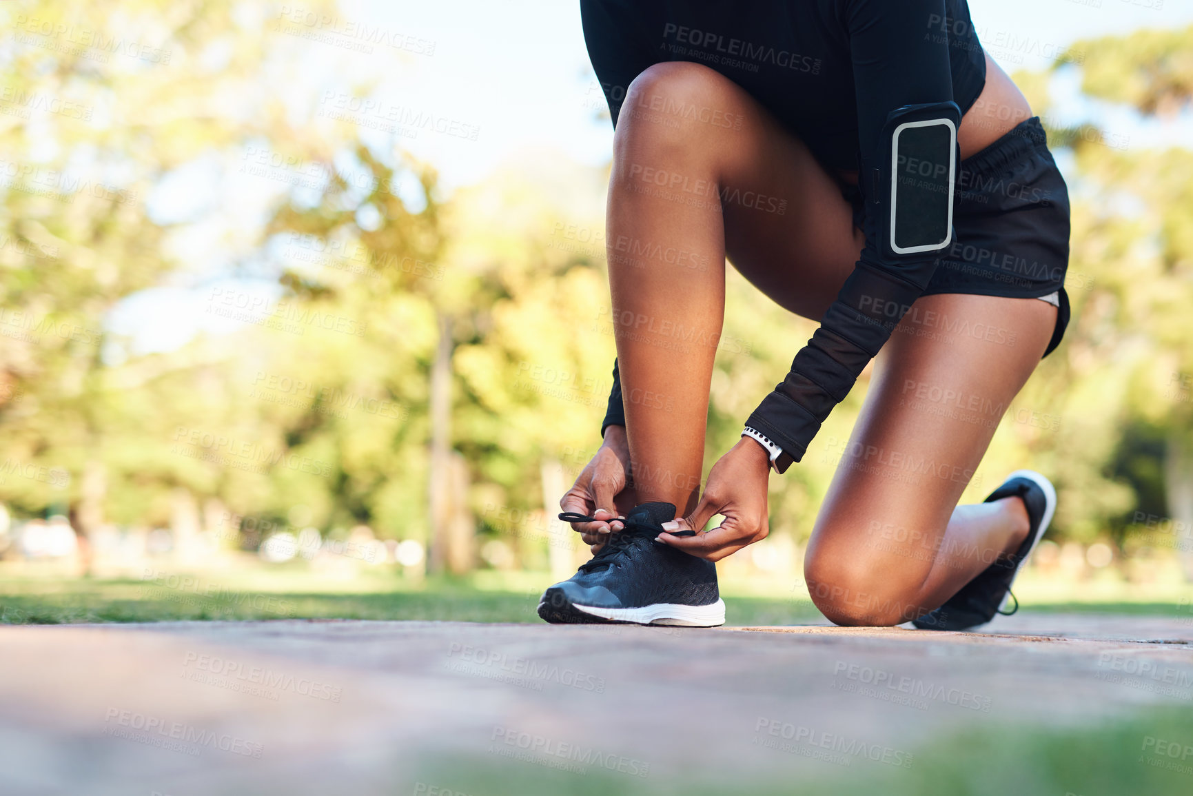 Buy stock photo Cropped shot of an unrecognizable young woman tying her shoe laces before her run in the park during the day