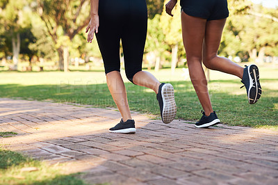 Buy stock photo Rearview shot of two unrecognizable young women running next to each other in the park during the day