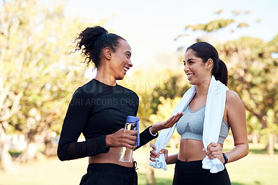 Buy stock photo Cropped shot of two attractive young women smiling at each other after their run in the park during the day