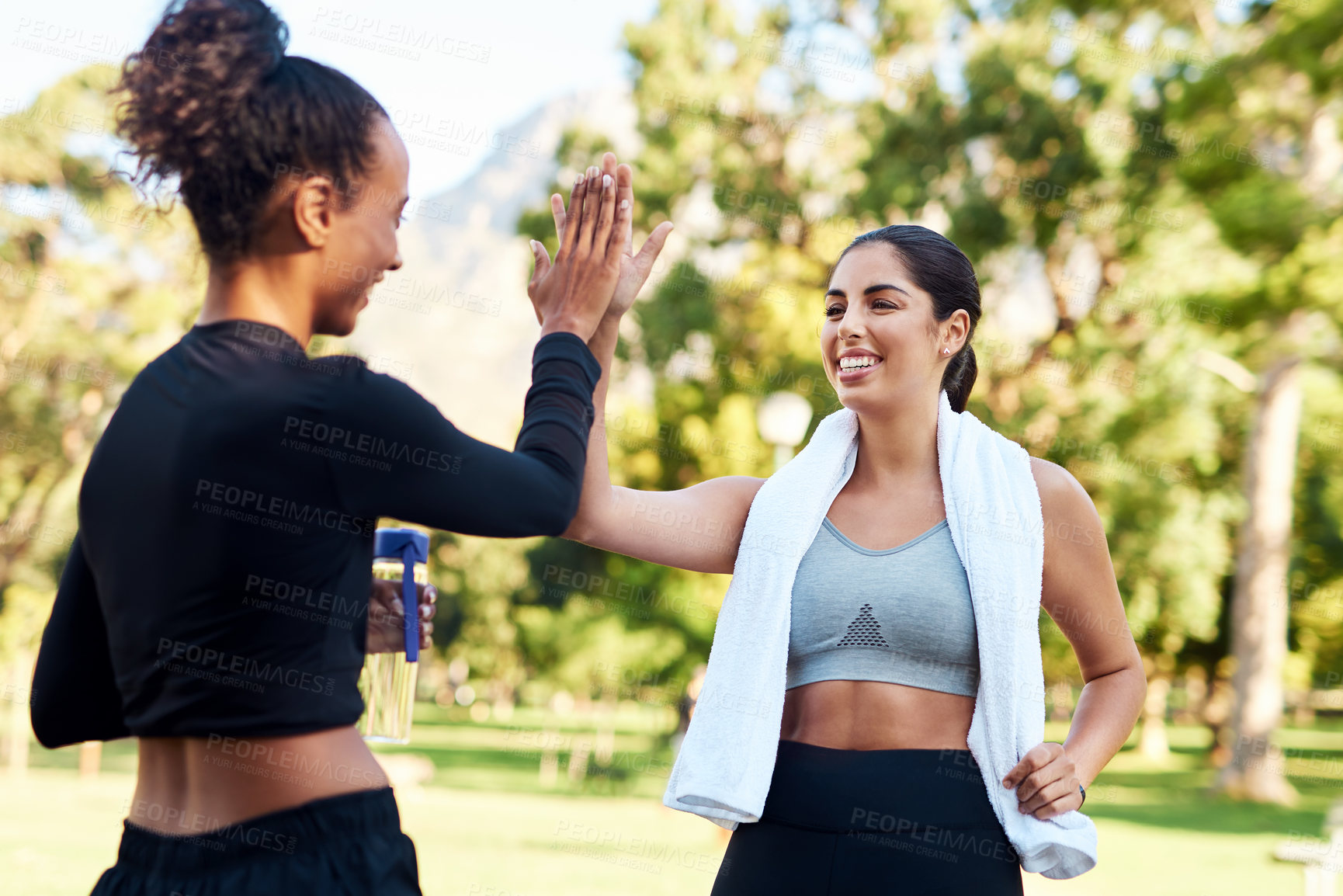 Buy stock photo Cropped shot of two attractive young women giving each other a high-five after their run in the park